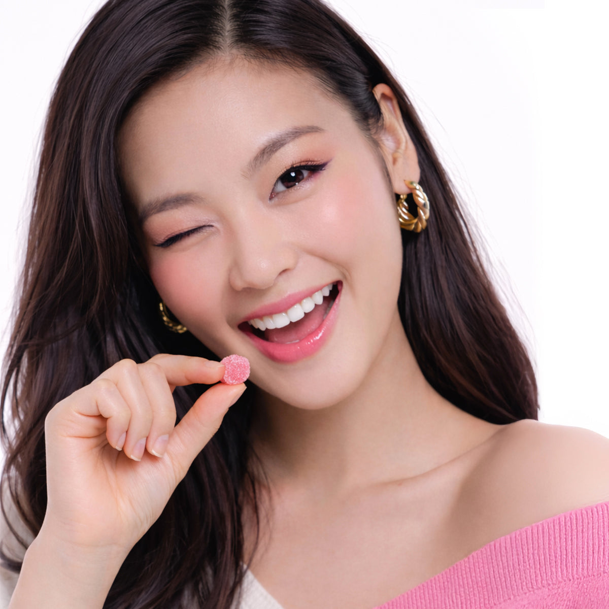 Woman with a bright smile and pink lipstick holding a mochi gummy